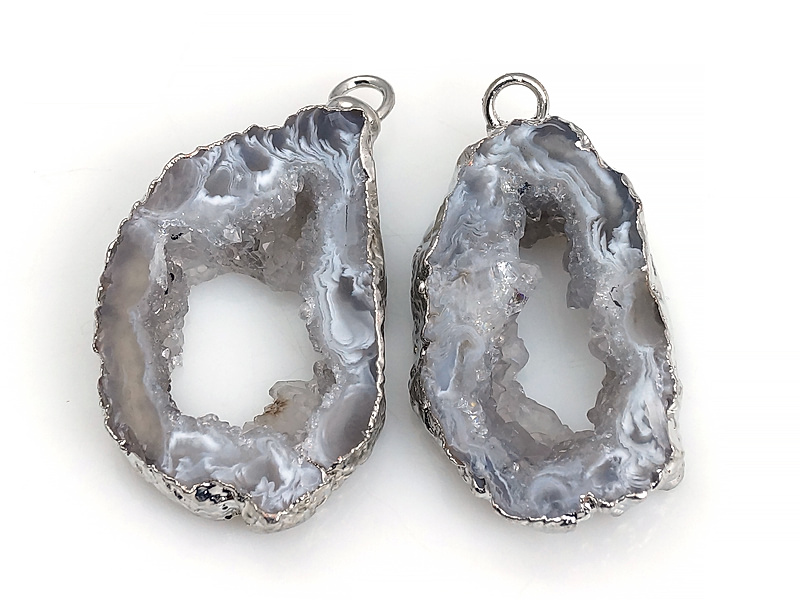 Пара подвесок срезов жеод морозного агата в оправе цвета "серебро". Месторождение - Бразилия. Подвес - 2 мм. Размеры и вес усреднены. Мелкие выемки.
