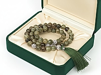 Набор материалов позволит собрать выразительные чётки из зелёного граната гроссуляра — минерала, известного своей природной палитрой и живой фактурой. Бусины обладают мягким, естественным блеском, а игра оттенков — от оливкового до глубокого хвойного — делает изделие визуально объёмным и благородным.&nbsp;
В комплект входят декоративные ажурные бусины, которые создают изящные акценты и формируют выразительный центральный узел. Шёлковая кисть насыщенного зелёного цвета идеально дополняет природную гамму гроссуляра и придаёт чёткам завершённый, аккуратный вид.&nbsp;

Характеристики

Тип изделия: набор для сборки чёток
Основной материал: бусины натурального граната гроссуляра
Диаметр бусин: 10 мм&nbsp;
Фурнитура: ажурные бусины и разделители с фианитами
Кисть: шёлковая, плотная, тёмно-зелёная
Стиль: этника, минимализм, медитативные аксессуары
Назначение: чётки, талисман, авторский аксессуар

С чем и как носить

Чётки из зелёного граната гроссуляра можно использовать как стильный аксессуар, гармонирующий с повседневными и этническими образами, либо как медитативный инструмент для практики концентрации и успокоения.&nbsp;
Их держат в руках, перебирают бусины во время молитвы, медитации или дыхательных упражнений. Благодаря благородной палитре гроссуляра такие чётки подходят и женщинам, и мужчинам, подчёркивают индивидуальность и становятся личным талисманом, который удобно носить с собой в сумке или на запястье, наматывая в несколько рядов.

Мастер - класс, как собрать четки, ЗДЕСЬ.&nbsp;
, фото №161262