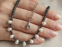 Набор материалов для чокера с волнистыми, рифлеными бусинами гематита и белыми зернышками натурального жемчуга. Основа для сборки - ювелирный тросик. Длина украшения регулируется цепочкой удлинителем на замочке карабине.

Как и с чем носить

Чокер с гематитом и натуральным жемчугом зернышком - украшение, которое легко вписывается в современный гардероб. Он красиво ложится по линии шеи, подчёркивая ключицы и создавая оригинальный акцент. Лучше всего носить его с открытым вырезом: V-образным, лодочкой или на голую шею.&nbsp;
Гематит добавляет образу графичности и глубины, а жемчуг смягчает впечатление и придаёт деликатный блеск. Чокер гармонично смотрится с лаконичными платьями, топами, шёлковыми блузами и жакетами, а в повседневных образах делает простые сочетания более выразительными. Его можно носить как самостоятельное украшение или сочетать с длинной цепочкой, создавая стильную многослойность.

Мастер-класс, как собрать чокер, ЗДЕСЬ.&nbsp;
, фото №162829