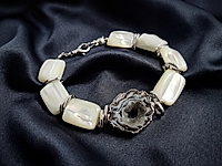 ЖЕОДЫ АГАТА В НАБОР НЕ ВХОДЯТ И ВЫБИРАЮТСЯ САМОСТОЯТЕЛЬНО ЗДЕСЬ.
Набор материалов для браслета с жеодой агата, белым перламутром и звеньями ювелирной цепочки. Длина браслета регулируется подбором нужного количества бусин перламутра, которого хватит и на серьги.
В качестве застежки использован карабин с вращающимся колечком под старину. Белые бусины квадраты разделяют крупные овальные звенья, снятые с ювелирной цепочки.
Мастер - класс, как собрать браслет на тросик с калотами, ЗДЕСЬ.
Как и с чем носить
Носите его с темным платьем, шелковой блузой или лаконичным костюмом, чтобы подчеркнуть контраст камней. Он гармоничен с жемчужными или перламутровыми сережками, тонкими кольцами и однотонной сумкой, уместен и в офисе, и для вечерних выходов.
, фото №162845